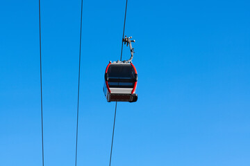 Single cable car gondola suspended on a cable against a clear blue sky. Minimalist composition with strong focus on one object and large copy space.  © Olga Lyubochkina