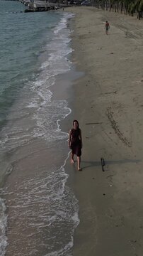 태국 방센 해변의 에메랄드빛 바닷가를 여유롭게 산책하는 젊은 여성의 뒷모습
