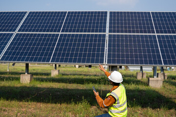 Field technician checking ground-mounted photovoltaic panels, using handheld device while adjusting array alignment, ensuring stable performance and efficient energy generation in outdoor conditions. © Kampan