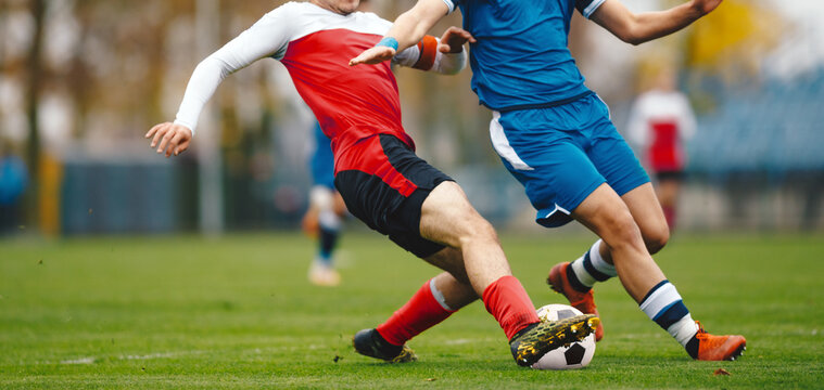 Soccer Players Competing for Ball with Slide Tackle on Grass Field. Adult Soccer Match Action