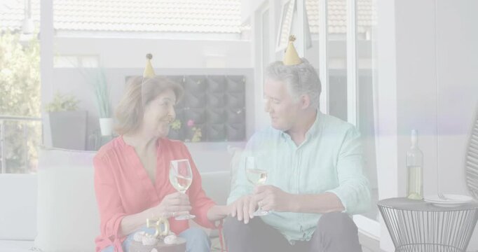 Couple clinking glasses and touching hands after toast, examining ring, celebrating 50th on porch
