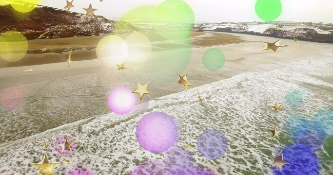 Crashing waves forming foam line over wet sand at aerial view, with colored bokeh, gold stars
