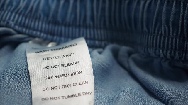Clothing care label instructions for washing and ironing denim fabric.