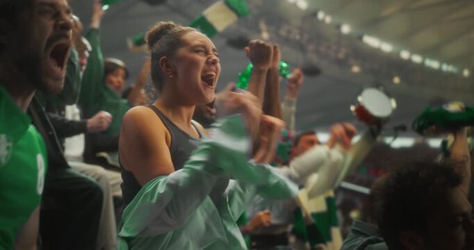 Close-up of a Young White Woman and Mixed Supporters in Green Apparel Celebrating in a Packed stadium Smiling, Shouting and Raising hands During a Professional League Football Cup Match. Slow Motion