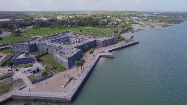 Low-altitude drone glide over the grassy ramparts and ancient watchtowers of the St. Augustine fort.