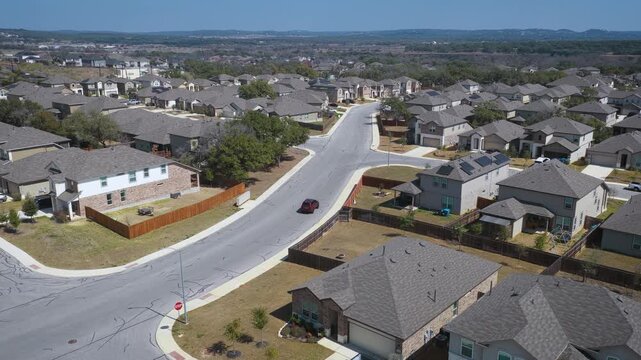 A car enters the neighborhood of Copper Canyon and drives through the curve towards their house passing many tract homes in the community. Drone footage of real estate in Bulverde, Texas.