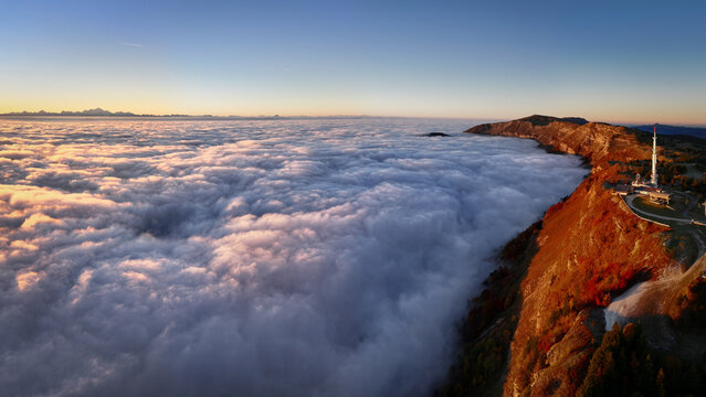 Aerial view of the clouds rolling over the Jura mountain range and Mont Blanc, a tower standing tall above, Gex, Auvergne-Rhone-Alpes, France