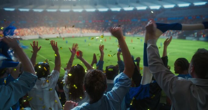 Rear View of Diverse Soccer Fans Celebrating in a Packed Stadium, Tossing Gold Confetti, Waving White Scarves, Clapping and Lifting Arms During a Professional International Championship Match Field.