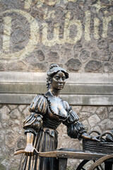 Obraz premium portrait close up shot of Molly Malone statue in Dublin, Ireland with stone textured wall behind on sunny winters day