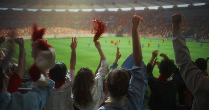 Back View of Diverse Football Fans Celebrating in a Packed Stadium, Raising hands, Clapping and Waving Scarves During a Professional International Championship Match and Cup Tournament. Slow Motion