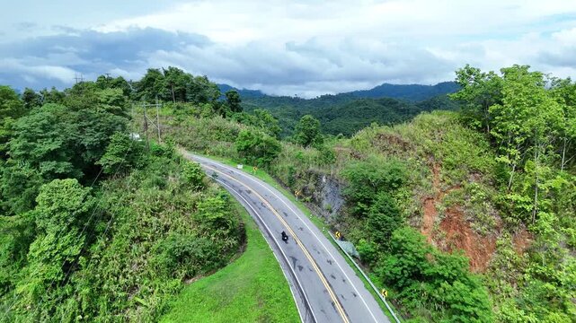 Winding Mountain Road with Lush Greenery and Cloudy Sky Serene and Adventurous Journey Through Scenic Hills and Forests