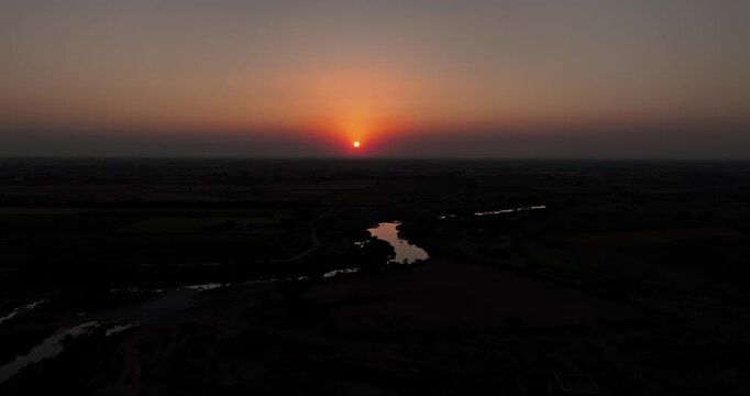 Stunning aerial view of a rural village surrounded by patchwork farmland during a golden sunset in Gujarat, India.