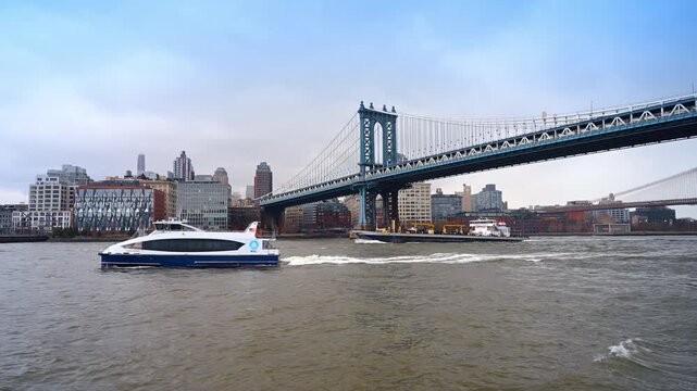 Modern motor boat and sludge boat move by the river near the Manhattan Bridge. Water transport in New York, USA.
