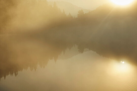 Tranquil morning sunlight illuminating soft fog over Lake Prebersee, Austria
