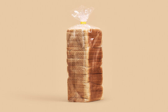 Loaf of sliced bread wrapped in clear cellophane against beige background
