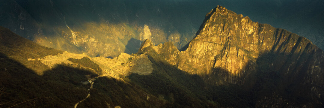 Aerial panoramic view of sunlight illuminating Machu Picchu, Intipunku, Peru
