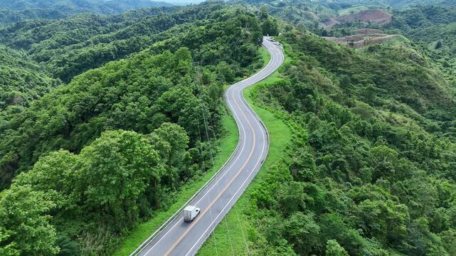 Winding Road Through Lush Green Mountains Scenic Travel Route with Vehicle Amidst Natures Beauty and Tranquility