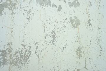 Fototapeta premium Close up of weathered peeling white paint on a worn surface with gray patches and cracks