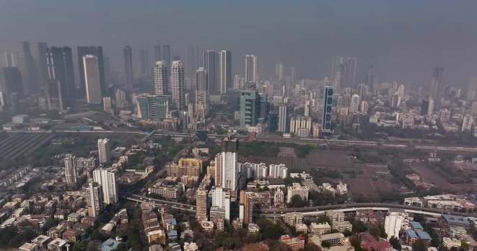Cinematic aerial view of the Mumbai city skyline during the monsoon season, with dramatic clouds creating a moody and atmospheric backdrop.