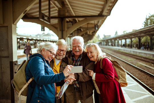 Senior friends taking a selfie at a train station