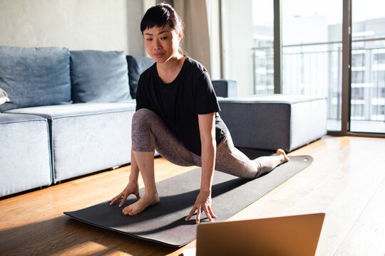 Woman practicing yoga stretch on mat at home