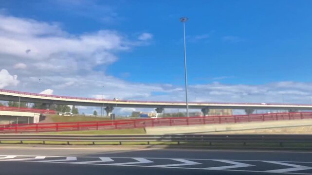 View from a moving car window of multilayer highway interchanges and overpasses. Urban transport infrastructure with concrete bridges, pillars and road network. Dynamic driving perspective