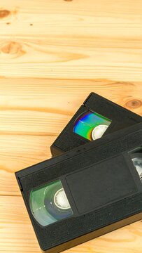 Close-up shot of two VHS tapes, with their spools visible. They're on a light wooden background, suggesting a nostalgic vibe
