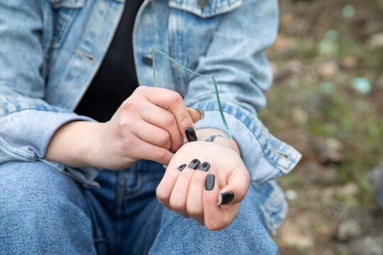 Girl cutting veins piece of glass.