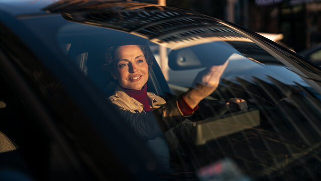 Smiling woman driving a car during golden hour