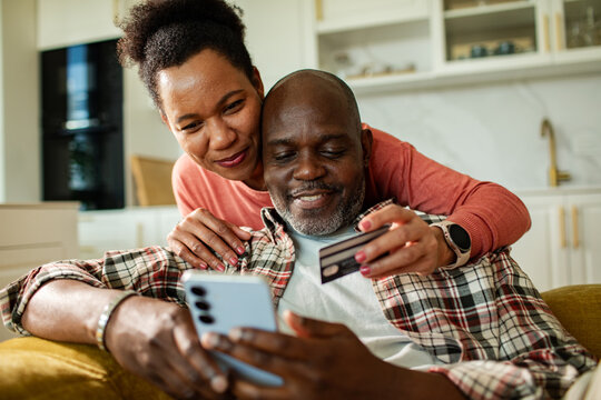 Happy couple shopping online at home with credit card and smartphone