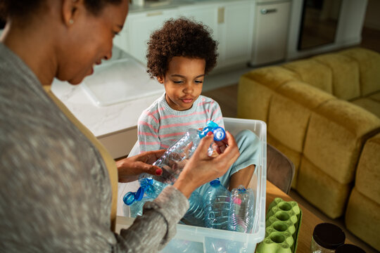 Mother and child sorting plastic bottles at home kitchen