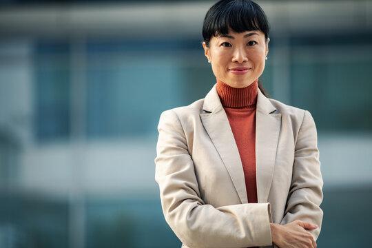 Confident businesswoman with arms crossed outside office building