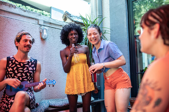 Friends laughing with drinks and ukulele on patio