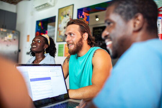 Diverse team brainstorming with laptops in casual coworking space
