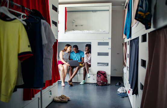 Friends using laptop in modern hostel dorm room
