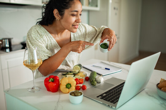 Woman following online cooking class at home kitchen