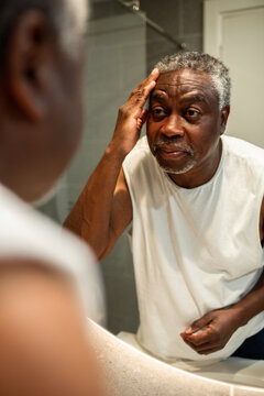 Senior man checking his face in bathroom mirror at home
