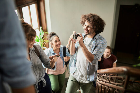 Friends laughing on indoor stairwell as one takes a photo