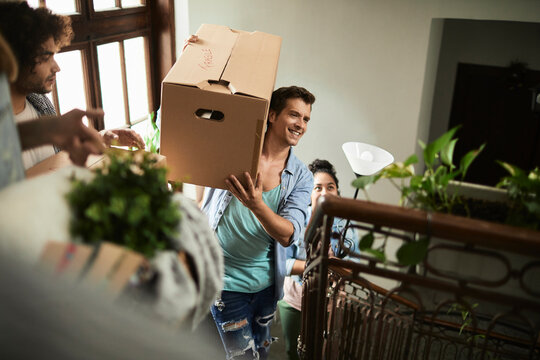 Friends carrying moving boxes in apartment stairwell