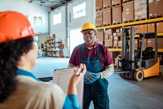 Warehouse workers discussing inventory checklist near forklift