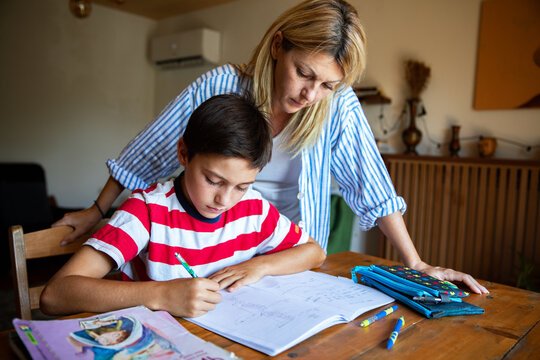 Mother tutoring son on homework at kitchen table