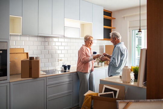 Senior couple unpacking boxes in new kitchen