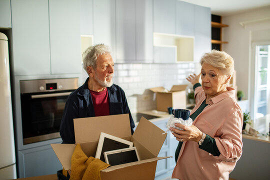 Senior couple unpacking moving boxes in kitchen