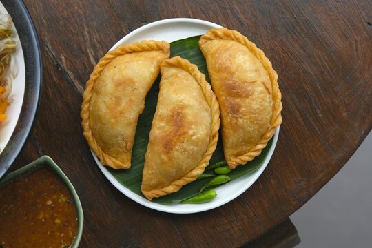 Pastel, Curry puff, Karipap, Epok-epok on plate. Popular snack in Indonesia, Malaysia or Singapore. Pastry filling potato, chicken and spice or vermicelli
