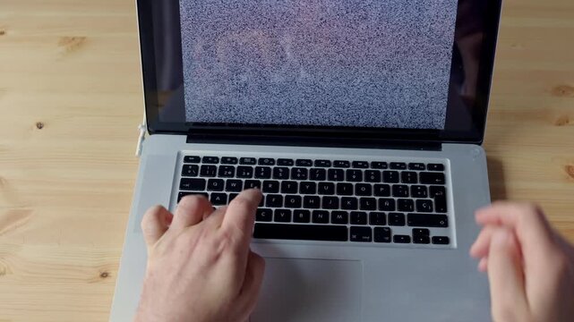 Close-up footage of a man repeatedly trying to unlock a laptop computer by typing on the keyboard. 