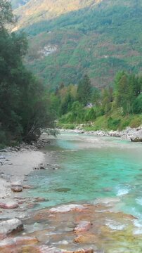 Drone flying above the Soca River near Trenta, rugged terrain and trees on sides, vertical shot
