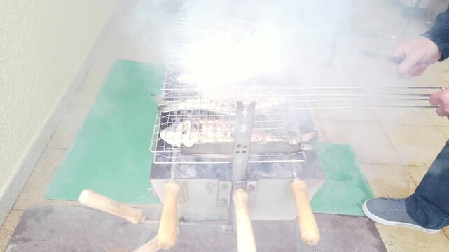 Fresh fish cooking on a barbecue grill over open heat. Close-up of whole fish grilling on a BBQ with natural fire and smoke. Outdoor seafood cooking with simple preparation and authentic atmosphere.