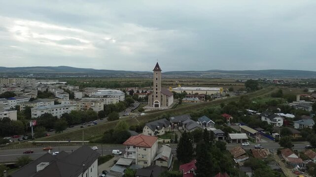 Aerial drone footage capturing a Catholic church in Bacau, Romania, surrounded by residential buildings, greenery, and urban infrastructure.