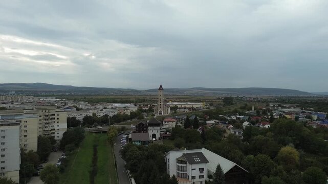 Aerial drone footage capturing a Catholic church in Bacau, Romania, surrounded by residential buildings, greenery, and urban infrastructure.