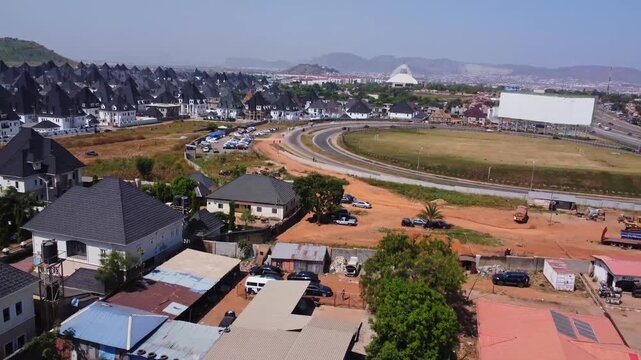 Drone flying over shacks and a busy highway towards a beautiful suburban neighborhood in Abuja, Nigeria